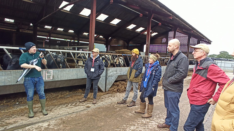 A group of people standing outside a barn on a farm