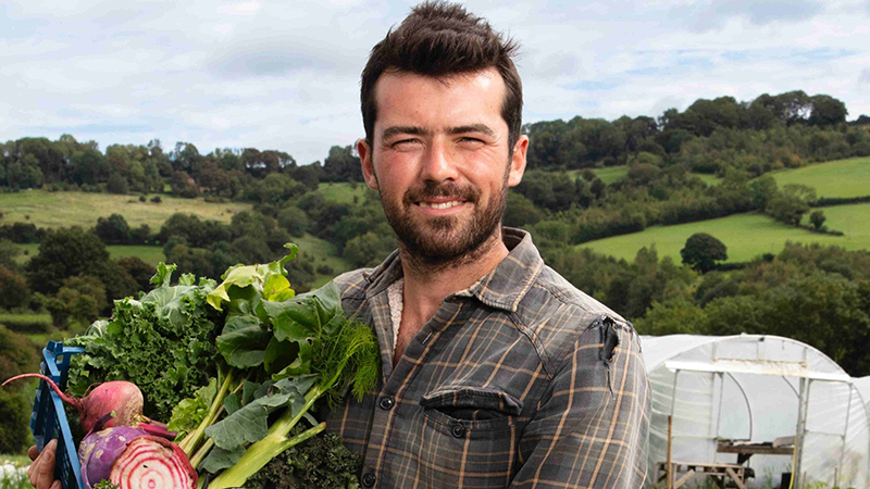 Hamish standing in field with a box of vegetables