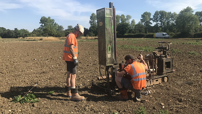 Two people with boring machine in a field 