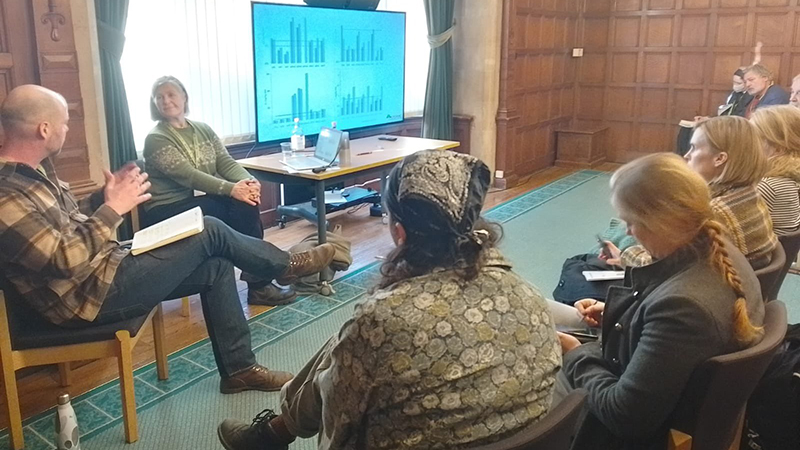 Two speakers and workshop participants in a panelled room