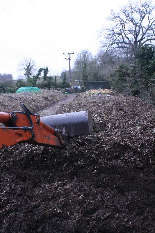 Woodchip compost windrow and digger used for turning the heap