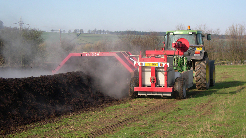 Tractor with compost turner aerating on-farm compost windrow.