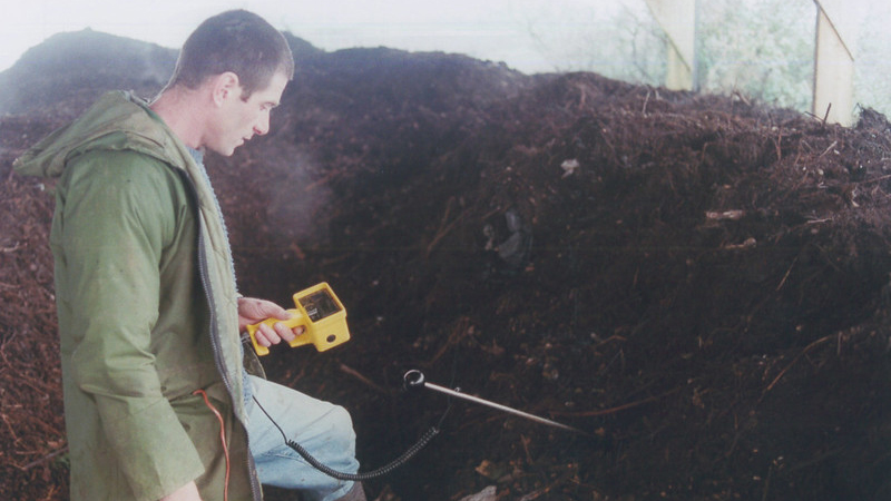 Man with temperature probe and pile of composting manure